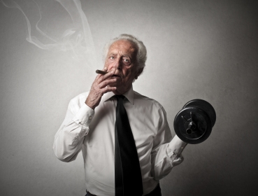 senior businessman smokes a cigar and does exercise